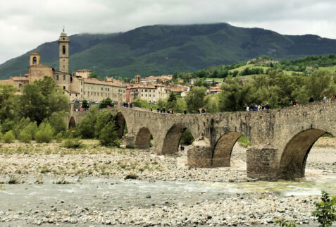 Bobbio - Ponte Gobbo or Ponte del Diavolo on Trebbia river in Val Trebbia. On the background Bobbio